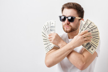 handsome serious man with beard in shirt holding a lot of hundre