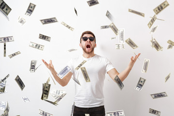 young happy man with a beard in white shirt standing under money