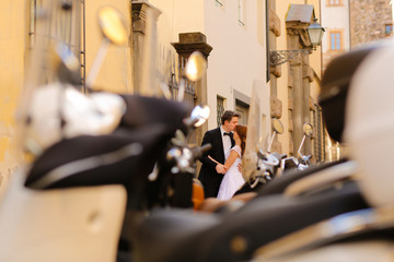 Fototapeta na wymiar Groom and bride in the city near mopeds, selective focus