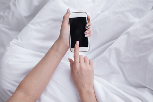 Closeup image of a teenager is searching information in network on mobile phone during free time. Young female student is revising photos on her cell telephone during break between lectures