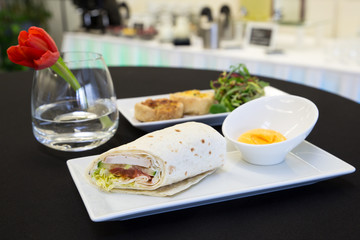 Chicken tortilla wrap with dip and two quiches on modern plates.