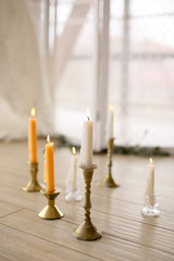 different candles white yellow orange gold and glass candle holders on table on white background