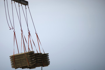 Three wooden products package pallet lifted by crane for loading onto a ship in port