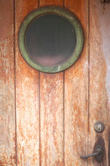 Old wooden door with a porthole on the abandoned ship