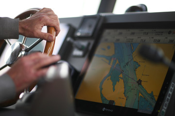 The hands of the captain and a steering wheel boat port services © Anna Jurkovska