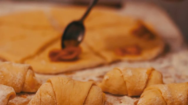 A woman puts on fresh pieces of dough apricot jam