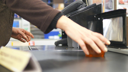 Shopper paying for products at checkout. Foods on conveyor belt at the supermarket. Cash desk with cashier and terminal in hypermarket. Working of cashier. Shopping at store. Close up