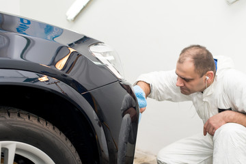 Fototapeta na wymiar Man on a car wash polishing car with a polish machine