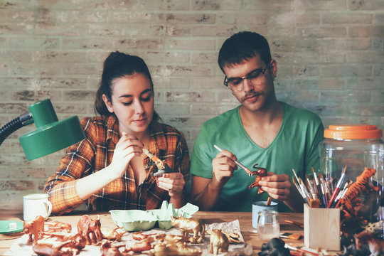 Young couple painting animal figurines with paint