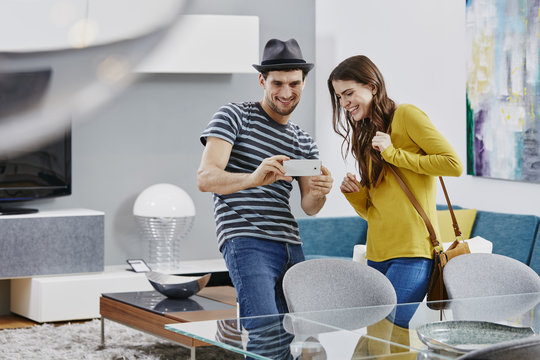 Couple in furniture store looking at dining table, taking pictures with smart phone