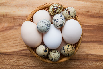 Raw quail and chicken eggs in a wicker vase closeup
