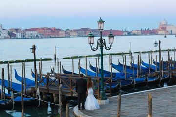 Obraz na płótnie Canvas Groom and bride in Venice Italy near gondola