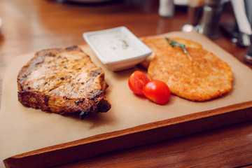 pork steak with hashbrowns on a wooden plate in restaurant