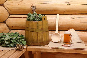 Кружка светлого пива стоит на скамейке в интерьере русской бани.