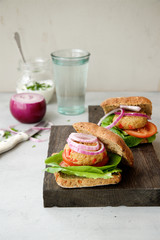Vegan burger with quinoa cutlet, salad and vegetables. Gray shabby wooden background 
