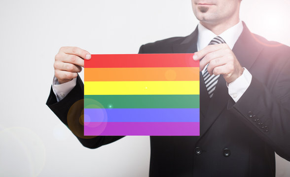 Man in business suit holding LGBT flag in hands. Free space for your text