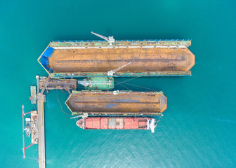 container ship in import export and business logistic.By crane , Trade Port , Shipping.Tugboat assisting cargo to harbor.Aerial view.