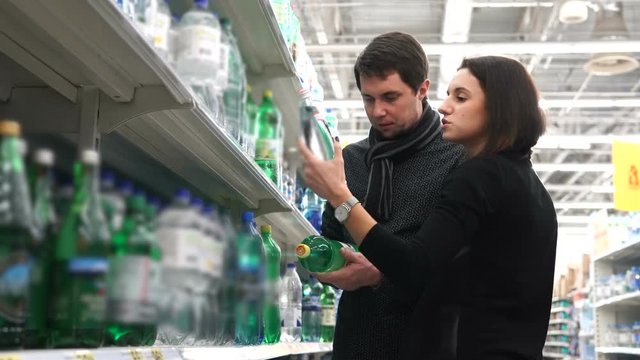 Young couple compare two bottles of water among themselves.