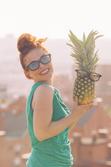 red hair woman holding a pineapple with glasses.