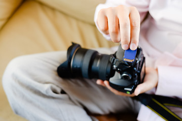 Closeup on person holding DSLR camera in hands. Top side view mock up background