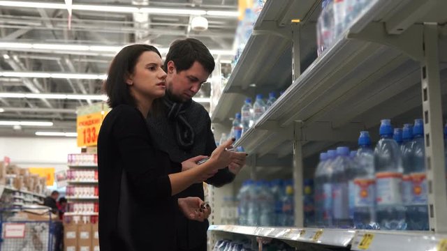 Young couple with enthusiasm choose mineral water for domestic use