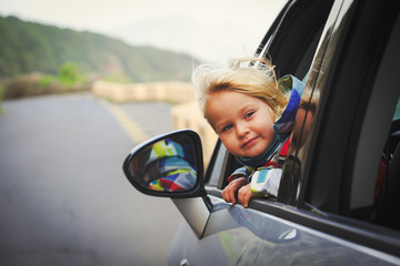 happy little girl travel by car on road