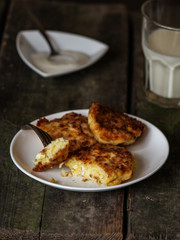pancakes with cottage cheese and corn (cheesecakes) with a glass of milk on the table
