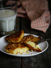 pancakes with cottage cheese and corn (cheesecakes) with a glass of milk on the table