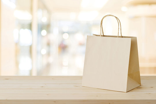 Brown paper shopping bag on wood table over blurred store background