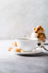 White cup of coffee with amaretti cookies on light gray background with copy space.
