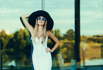 Fototapeta premium Beautiful and elegant blond woman smiling in a hat and sunglasses. copyspace