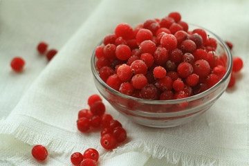 Berries cranberries glass plate in front of a white linen cloth, close-up, selective focus