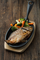 Baked fish dorado with vegetables in a frying pan