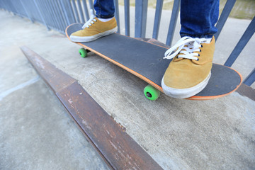 young skateboarder legs riding skateboard at skatepark ramp