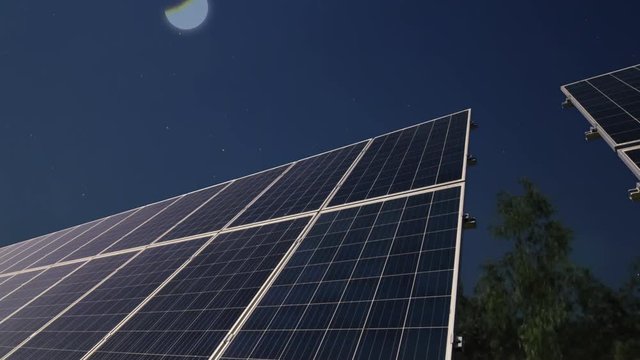 Solar panels at night with the moon before the sun rising