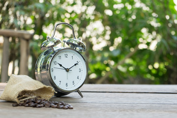 alarm clock with coffee beans on wooden table with morning light, Start up concept