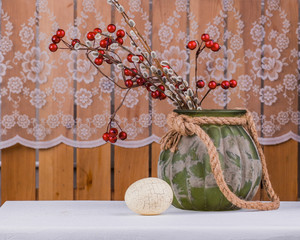 Still life with Easter egg, bouquet of willow branches and red berries.
