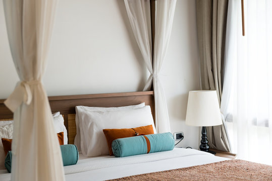 resort style bedroom with white sheet, brown and blue pillow