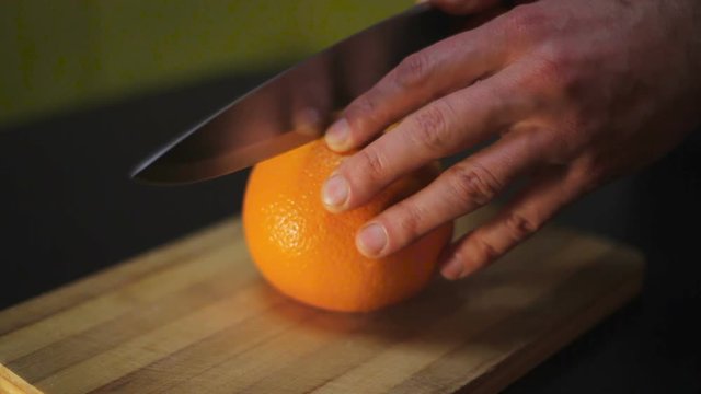 man cut the orange on a wooden board