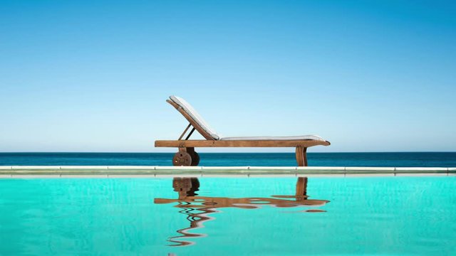 Seamless loop - Reclining chair near a swimming pool, sea and blue sky, water reflections, video HD