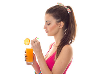 profile of young beautiful brunette girl in pink shirt drinks orange cocktail and smiling on camera isolated on white background