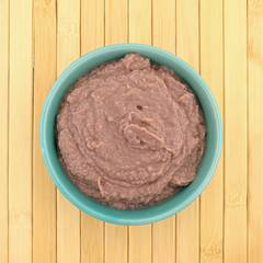 Yogurt berry smoothie in a green bowl atop a wood place mat.