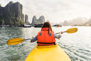 Young woman traveler paddling the kayak in the tropical bay, Travel concept