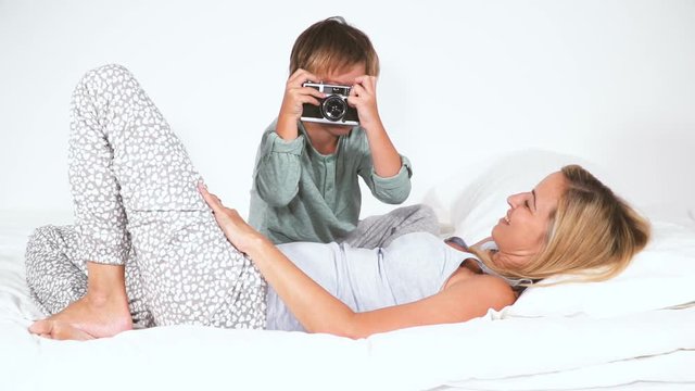 4 j&auml;hriger bub liegt mit seiner mutter im bett und fotografiert
