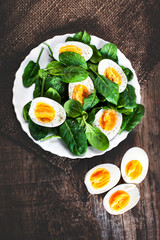 Healthy Salad - spinach baby leaves and boiled eggs cut in a half on wooden table with copyspace..