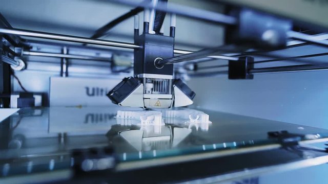 Super close focus on micro 3d printer head at work, printing small details with white filament, quickly moving inside glass box, futuristic shot. Industrial business concept, left side view
