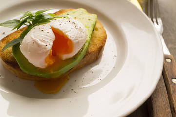 a poached egg with toast and avocado. cut. closeup
