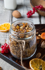 Homemade granola with nuts and dried oranges in jar on wooden background