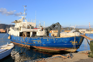 Fototapeta na wymiar Old blue and white fishing boat docked in the harbour of La Spezia in Italy.