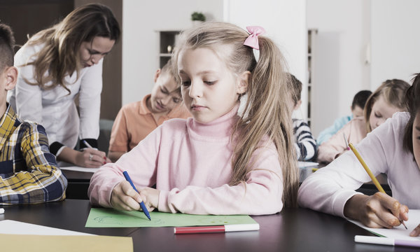 Girl and  children in elementary age at drawing lesson